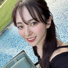 a woman holding an umbrella next to a swimming pool