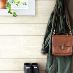 a coat, boots and purse hanging on a wall next to a potted plant