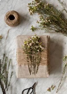 flowers and scissors on a table with twine, spools of twine