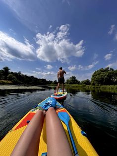 a man riding on the back of a yellow surfboard next to a woman's legs