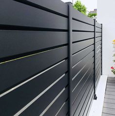 a black fence with white lines on the side and flowers in pots next to it