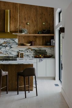 a kitchen with marble counter tops and wooden cabinets, along with two bar stools