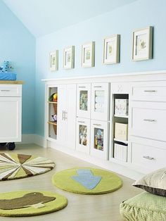 a child's bedroom with blue walls and green rugs on the floor in front of white cabinets