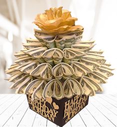 an origami flower made out of money on top of a wooden table with the words happy birthday written below it