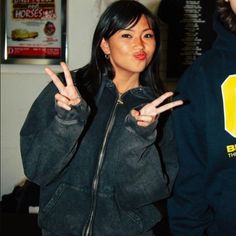 a woman making the peace sign with her hands while standing in front of a man