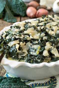 spinach and artichoke casserole in a white dish on a wooden table