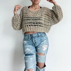 a woman wearing ripped jeans and a cropped sweater is posing for the camera with her hand on her head