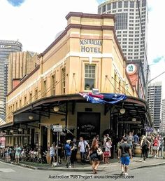 people are walking around in front of a building with an australian flag on the roof