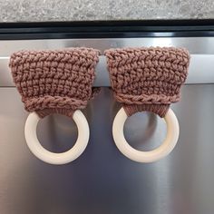 two crocheted napkins are attached to the handles of a dishwasher