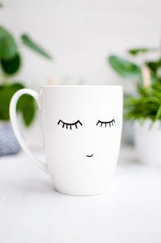 a white coffee cup with eyelashes painted on it