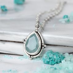 A glistening teardrop of aquamarine gemstones suspends from a delicate chain in this stunning necklace. The vibrant blue-green hue adds a pop of color to any outfit, making it a versatile accessory for any occasion. The simple yet sophisticated design is sure to become a go-to piece in your jewelry collection. This necklace features a natural, genuine, unique gemstone handpicked from our current collection. The actual gemstone you receive will be one-of-a-kind and may be different from the photo Affordable Sterling Silver Crystal Necklace Gift, Affordable Large Pendant Sterling Silver Necklace, Affordable Sterling Silver Crystal Necklaces For Gifts, Cheap Sterling Silver Gemstone Jewelry, Cheap Silver Crystal Necklaces With Natural Stones, Palm Necklace, Silver Necklace For Women, Sterling Silver Heart Pendant, Aquamarine Pendant