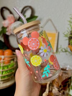 a person holding up a glass cup with strawberries, lemons and oranges on it