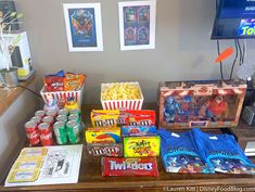 an assortment of snacks and drinks on a table in front of a flat screen tv