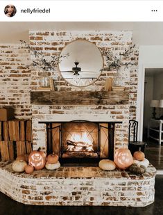 a brick fireplace with pumpkins on the mantle