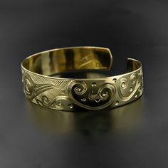 "Hand-engraved and made-to-order, this 'Hummingbird' cuff is a rare mixture of traditional Northwest Native style aesthetics and modern design. It depicts a bird in flight, with complex scrollwork representing flowers and flora. It measures 1/2\" wide by 6\" long, which will fit an average female wrist. Most wrists are between 6 1/4\"-6 3/4\" in circumference. This cuff can also be adjusted (or shaped) quite easily. It is signed by Kelvin Thompson and comes with a formal fine art appraisal, as w Artisan Gold Bracelets Engraved, Artisan Gold Bracelet Engraved, Artisan Gold Bracelet With Engraved Details, Artisan Gold Engraved Bracelets, Artisan Engraved Gold Bracelets, Unique Gold Engraved Cuff Bracelet, Unique Gold Etched Cuff Bracelet, Unique Engraved Gold Cuff Bracelet, Artisan Gold Engraved Cuff Bracelet