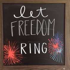 a chalkboard sign that says let freedom ring with fireworks in the sky behind it