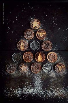 a christmas tree made out of cookies sitting on top of a black surface with white sprinkles