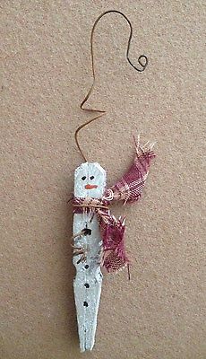 a snowman ornament hanging from a string on a brown surface with a red and white ribbon