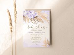 a baby shower is displayed on a wall next to some dried flowers and pamylons