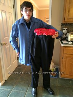 a man in blue shirt and black pants holding up a fake red piece of meat