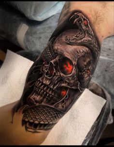 a man's arm with a skull and snake tattoo on it