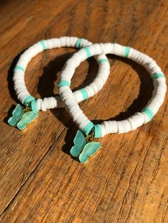 two white and green bracelets sitting on top of a wooden table next to each other