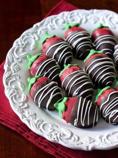 chocolate covered strawberries are arranged on a white plate with green sprinkles