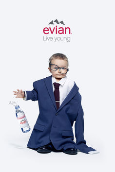 a little boy in a suit and tie with a bottle of water on his feet