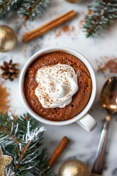 a cup of hot chocolate with whipped cream on top and cinnamon sticks in the background