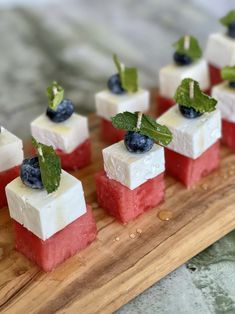 small red, white and blue desserts are arranged on a cutting board with mint leaves