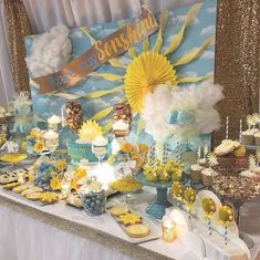 a table topped with cakes and desserts covered in yellow frosting next to a banner