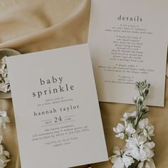 a baby sprinkle is laying next to some flowers on a bed with sheets