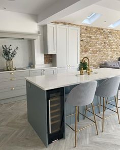 a kitchen with white cabinets and marble counter tops next to a bar in the middle