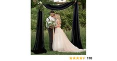 a bride and groom standing under an arch with black draping on the side