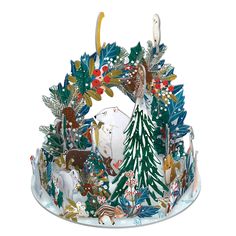 a christmas cake with frosting and decorations on it's top, surrounded by other holiday items