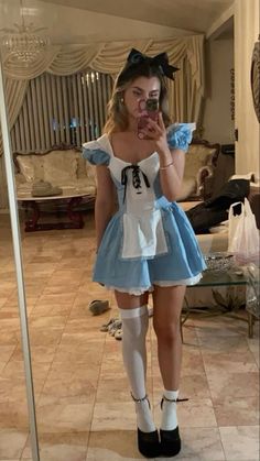 a woman is taking a selfie in front of a mirror wearing an alice costume