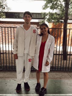 two people standing next to each other in front of a fence