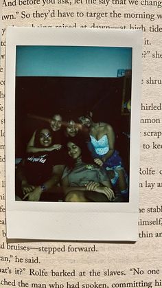 a group of people sitting together in front of a book page with an old photo on it