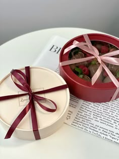 a red box filled with chocolates on top of a white table next to an open book