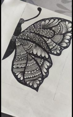 a drawing of a butterfly sitting on top of a piece of paper with black ink