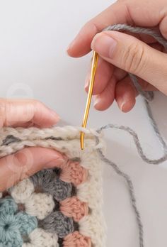 someone is crocheting together with yarn and knitting needles