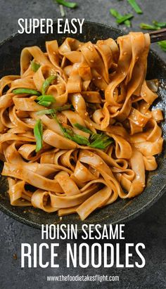 a bowl filled with noodles and sauce on top of a black table next to chopsticks