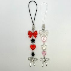 two necklaces with bows and hearts attached to them on a white surface, one has a red bow