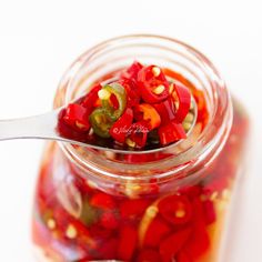 a spoon full of pickled peppers in a jar