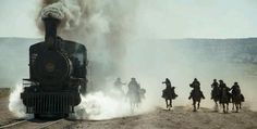 a group of men riding on the backs of horses next to a steam engine train