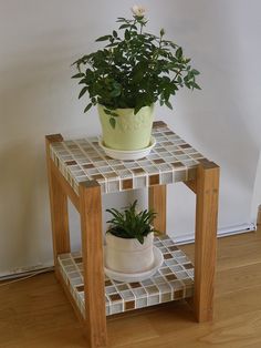 a potted plant sitting on top of a small table next to a wall and wooden floor