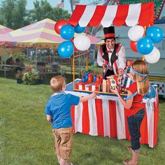 two children and an adult standing at a table with balloons in the shape of clowns