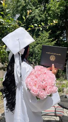 a graduate holding a bouquet of pink roses