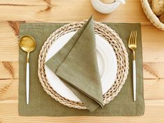 a place setting with napkins, silverware and gold utensils on a wooden table