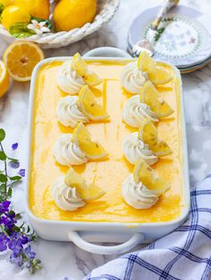 a dish with lemons and meringue in it on a table next to flowers